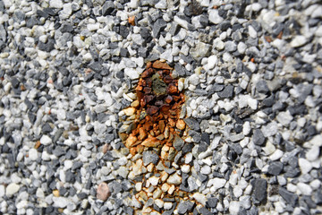 Wall covered in small blue and white rocks bleeding rust from a hole.