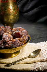 Big luxury dried date fruit in bowls on a linen napkin, kurma ramadan kareem concept, close up.