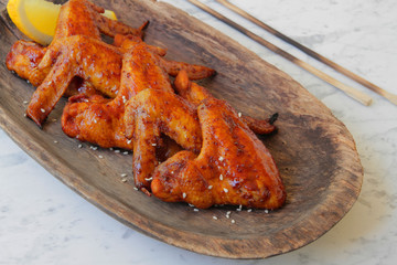 
fried chicken wings with spices and sesame seeds on a wooden plate.