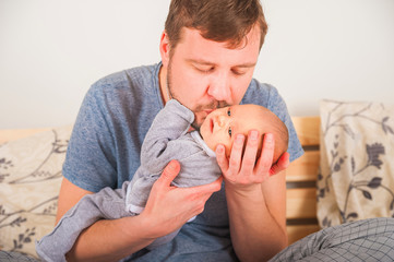 Father and newborn in Scandi bedroom interior. The father sings a lullaby to the child. Parent...