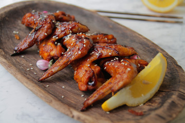 
fried chicken wings with spices and sesame seeds on a wooden plate.