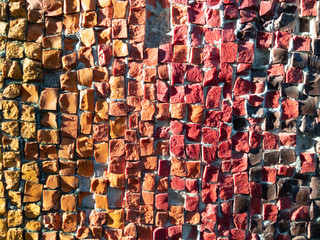 Mosaic wall decoration with orange and red elements. Texture with shadows.
