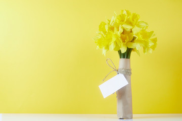Bouquet of yellow spring flowers. Bunch narcissus packed craft paper with greeting card.Spring card for Mother's Day © wertinio