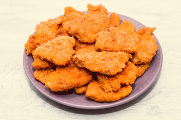 on the kitchen white table fried chicken strips in breaded prepared in the home kitchen. close up