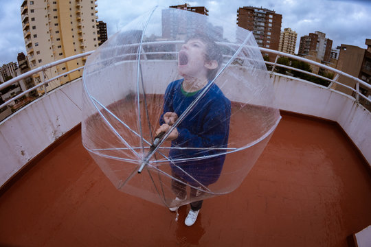 Ni&ntilde;o grita al cielo dia de lluvia paraguas trasnparente