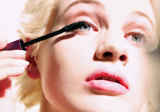 Close up young woman applying mascara