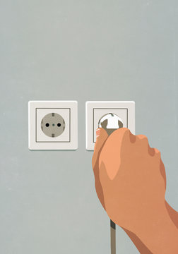 Hand plugging cord into electrical outlet