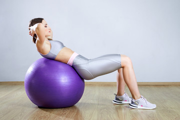 Young fit woman exercising in a gym. Sports girl is training cross fitness with Pilates Balls.