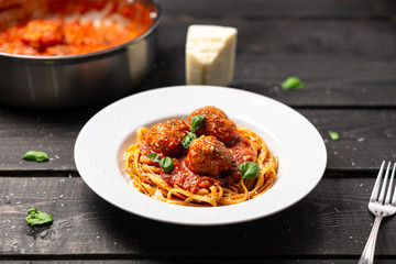 Spaghetti meatball plate stock photo. Italian pasta dish served in white plate on black wooden background. Spaghetti and meatballs is like bolognese sauce with balls of meat cooked in tomato sauce.