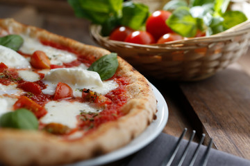 Pizza mit Büffelmozzarella-Geschmack, über einem Holztisch mit Tomaten im Hintergrund