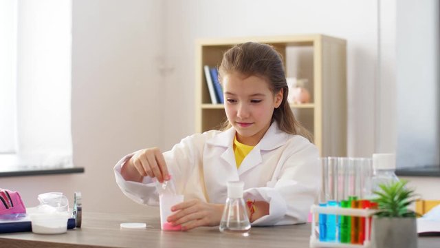 chemistry, science and childhood concept - girl with powder and water playing and making slime at home laboratory