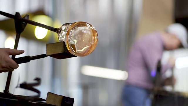Close-up footage of craftsman shaping the beautiful molten glass extracted from the furnace located at a glassmith glass and crystal workshop. International workers dat / Labour day.