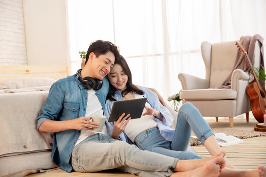 The young couple sitting on the floor use tablet computers