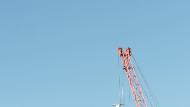 Time lapse of the crane at the construction site against the blue sky.