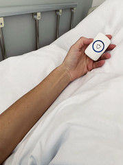 Female patient holding nurse call button in hospital room