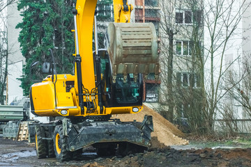 Excavator on a construction site against the background of the city
