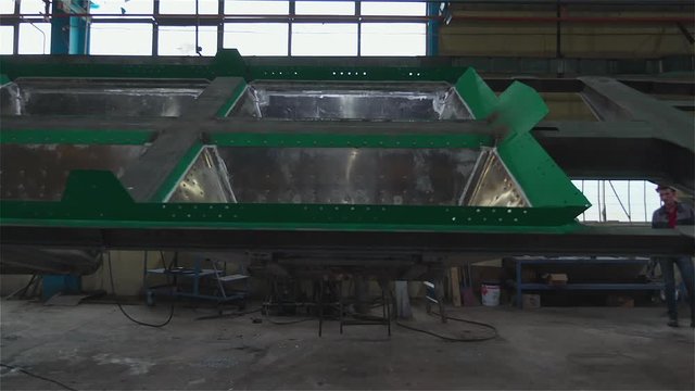 Worker Behind Huge Green Steel Part Of Future Wagon