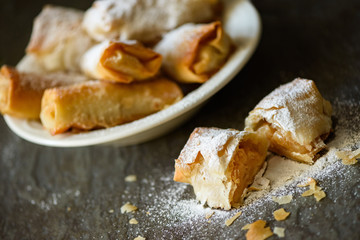 Apple rolls  powdered with sugar arranged in a ceramic bowl .