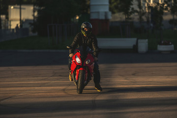 View of a man in helmet sitting on red sports motorcycle on a asphalt road.