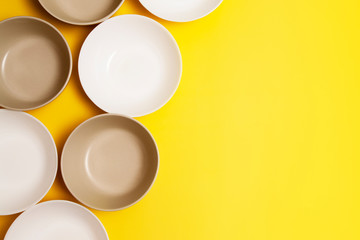 Top view plates on yellow background with copy space
