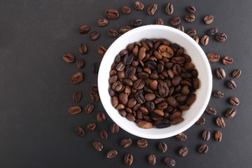 Coffee beans and bowl on stone background. Top view with copy space for your text