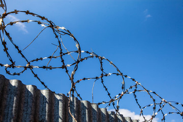 barbed wire over a high fence protects against illegal entry into the territory