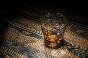 glass with whiskey and ice on the table
