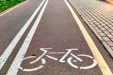 Bicycle white and yellow lanes sign and image of a bicycle with sun rays on road surface