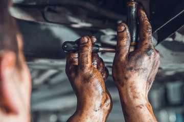 dirty male hands with torque wrench. technician repairing a car in a workshop
