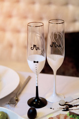 Two glasses of champagne are on the wedding table. The glasses are next to each other and they say Mr and Mrs