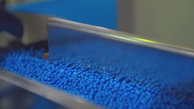 movement of blue plastic granules in production equipment.closeup.