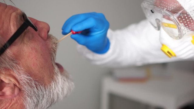 Clouse Up Elderly Man Takes A Coronovirus Test. Doctor In A Protective Suit Takes A Swab From The Throat. Non-invasive Testing Method. Rapid Test Covid 19