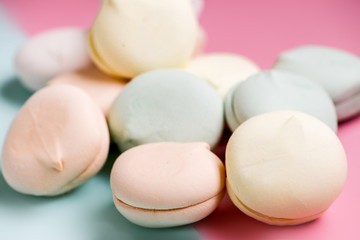 Colored sweet dessert zephyr marshmallows on pink & blue background. Air marshmallows. Close up, foo? photography
