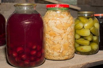 Jars with blanks are in the basement. Jar with cherry compote. Jar of pickled mushrooms. Jar of pickled cucumbers. Very tasty natural food. Vegetarianism.