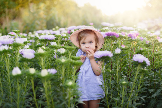 Outdoor portrait. Little toddler lovely girl with flowers at beautiful garden. child outdoors in nature