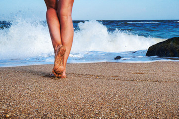 Female legs on the sea beach, footprints in the sand, vacation and travel concept.