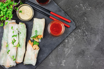 Spring roll with vegetables, shrimp and microgreen radish. A healthy asian snack on a black concrete background. Photo with copy space