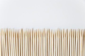 Wooden toothpicks in a row look like a fence on a white background