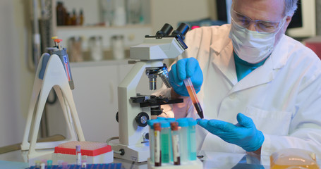 A virologist in a small laboratory observes a sample of blood plasma he is working with in tests...