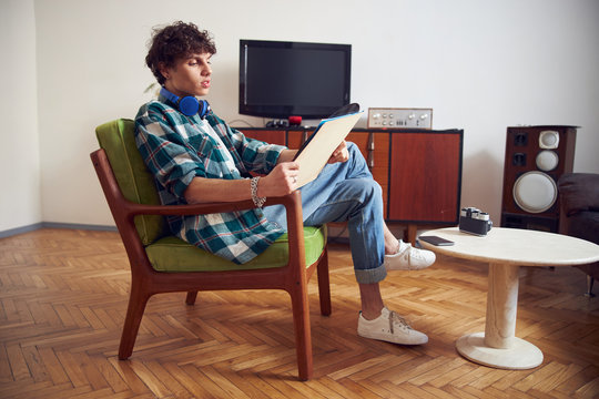 Handsome Young Man With Vinyl Record Sitting In Armchair At Home