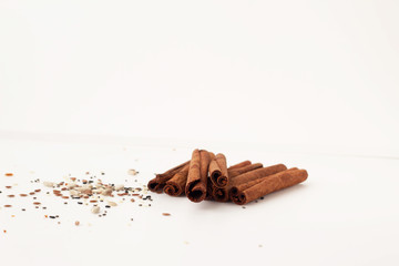 Close-up of cinnamon sticks and seeds on a white back