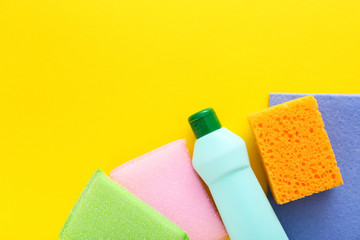 Colorful cleaning set for different surfaces in kitchen on yellow background. Top view, flat lay