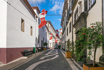 One of the narrow streets with Christmas decoration and typical Portuguese pavement in Funchal, Madeira