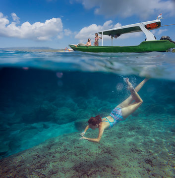 Young woman snorkeling near the boat in ocean, underwater view