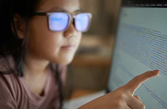 Close-up view of a girl reading code on the monitor