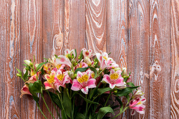 Fototapeta na wymiar Alstroemeria on the wooden background. flowers on a brown background. copy text. beautiful bouquet.