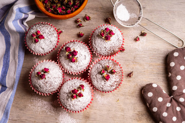 Chocolate muffins with powdered sugar and decor of dried tea roses.