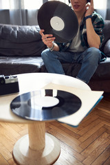 Young man sitting on couch and holding vinyl record