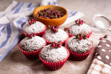 Chocolate muffins with powdered sugar and decor of dried tea roses.