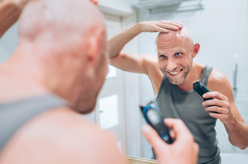 Hairless man satisfied with his new style haircut he making using an electric rechargeable Trimmer...